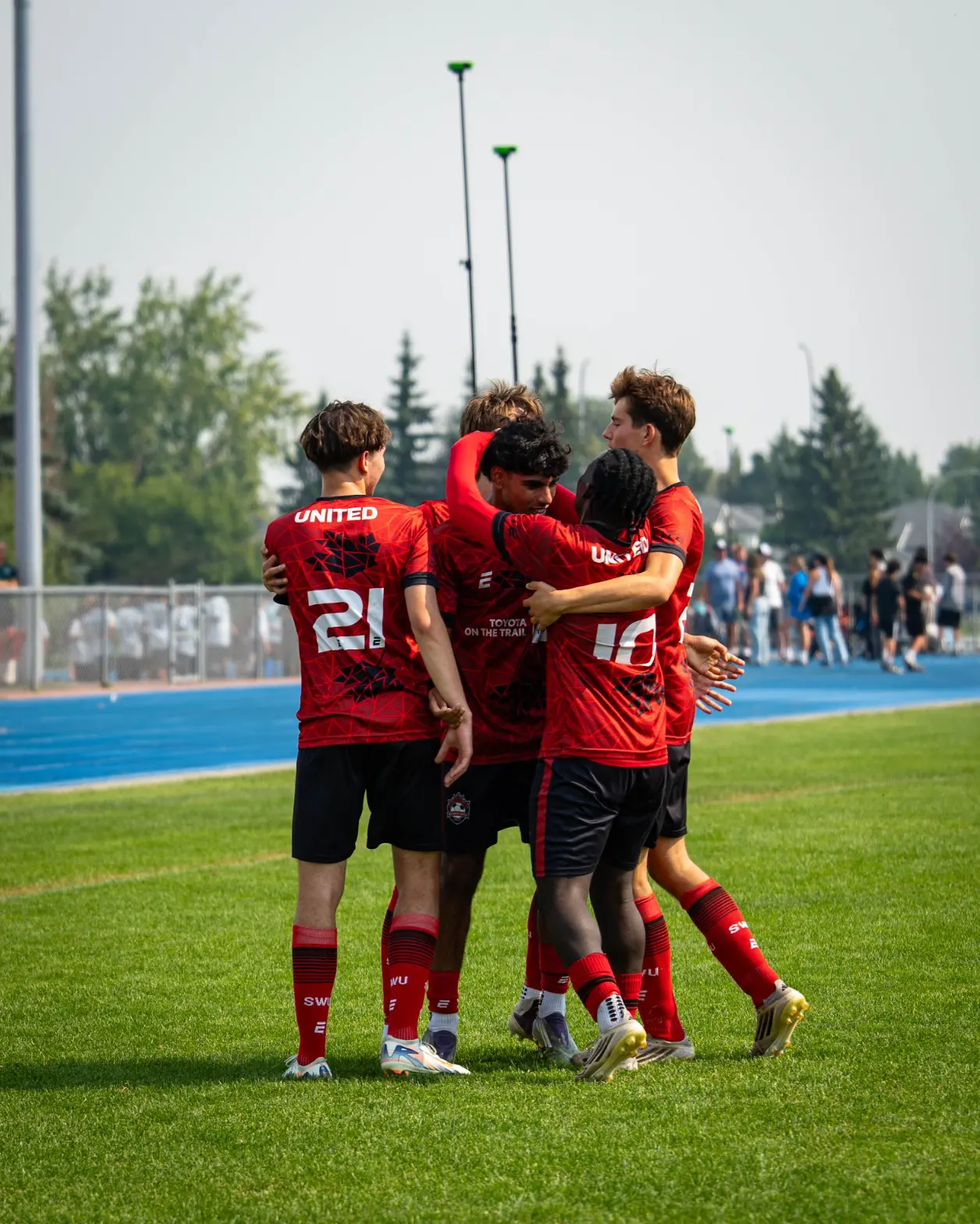 Southwest United players celebrating together in a huddle on the field